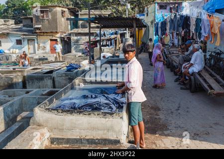 Ein Dhobi Wallah (Washerman) arbeitet Waschmittel in einem typischen Betonwaschstift in Mahalaxmi Dhobi Ghat, einem großen Open-Air-Waschsalon, Mumbai, Indien Stockfoto