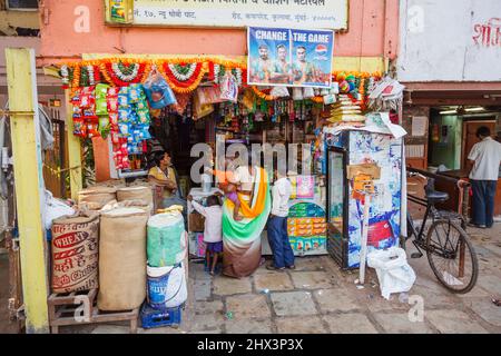 Eine einheimische Frau in einem Sari mit kleinen Kindern, eine Kundin in einem Lebensmittelgeschäft außerhalb von Mahalaxmi Dhobi Ghat, einer großen Open-Air-Wäscherei in Mumbai, Indien Stockfoto