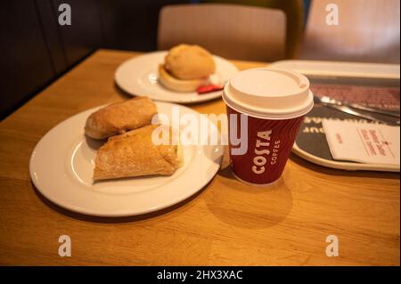 Costa Indoor Tisch mit costa Tasse Kaffee, Bacon Roll, costa Panini und Serviette auf Tablett Stockfoto