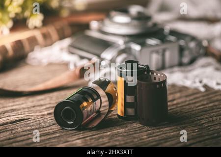 Nahaufnahme alte 35 mm Filmrolle auf Holztischplatte mit Vintage-Kamera im Hintergrund. Stockfoto