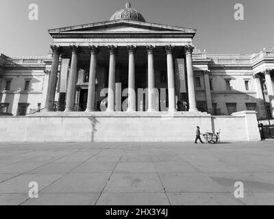 London, Greater London, England 08 2022. März: Müllsammler geht vor der National Gallery am Trafalgar Square vorbei. Monochrom. Stockfoto