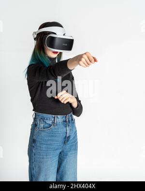 Teenager-Mädchen mit vr Headset Stanzen, kämpfen mit jemandem im Spielbereich, virtuelle Realität auf weißem Hintergrund, vertikalen Rahmen. Das Konzept des m Stockfoto