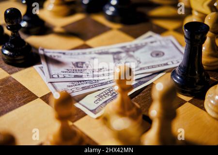 Geld in US-Dollar-Scheinen auf einem alten Schachbrett mit Retro-Schachfiguren Stockfoto