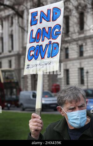 London, Großbritannien. 09. März 2022. Ein Protestler hält während der Demonstration ein Plakat hoch, das Nachforschungen und ein Ende von Long Covid-19 fordert.Eine Protestgruppe auf dem Parliament Square fordert die Regierung auf, etwas Geld in die Erforschung von Long Covid-19 zu investieren. Sie sagen, dass viele Menschen aufgrund gesundheitlicher Komplikationen nach der Exposition gegenüber Covid-19-Varianten in den letzten zwei Jahren lebensverändernde Verletzungen erleiden. Kredit: SOPA Images Limited/Alamy Live Nachrichten Stockfoto