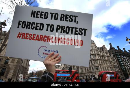 London, Großbritannien. 09. März 2022. Ein Protestler hält während der Demonstration ein Plakat hoch, auf dem er die Erforschung von Long Covid-19 fordert.Eine Protestgruppe auf dem Parliament Square fordert die Regierung auf, etwas Geld in die Erforschung von Long Covid-19 zu investieren. Sie sagen, dass viele Menschen aufgrund gesundheitlicher Komplikationen nach der Exposition gegenüber Covid-19-Varianten in den letzten zwei Jahren lebensverändernde Verletzungen erleiden. Kredit: SOPA Images Limited/Alamy Live Nachrichten Stockfoto