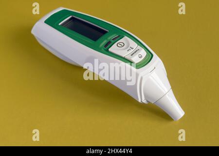 Infrarot-Stirn- und Ohrthermometer für Baby, Erwachsene, Krankenhaus mit Fieberalarm isoliert grün auf buntem Studiohintergrund lackiert. Objekt und Essen Stockfoto