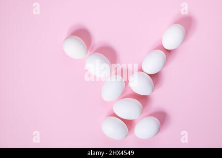 Weiße ostereier auf rosa Hintergrund. Draufsicht. Verschiedene Formen wie osterhase aus weißen Eiern. Frohe Ostern einfaches Konzept Stockfoto