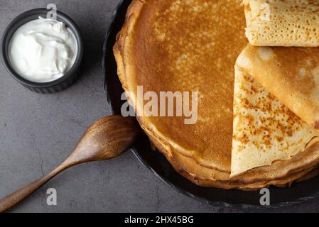 Ein Stapel dünner Pfannkuchen mit frischer Sauerrahm Stockfoto