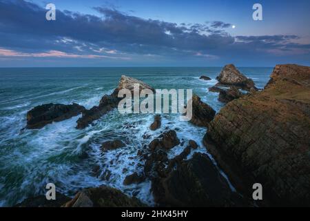 Atemberaubende Aussicht auf die Klippen im Mondschein auf die nordschottische Küste und raue Meere. Berühmte Felsformation an der Moray Coast, Scottish Highland Stockfoto