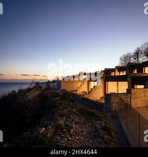 Abenddämmerung im Außenbereich, Luftansicht der beleuchteten Fenster und privater Sitzbereich und Aussichtsplattform mit Meerblick und Sonnenuntergang. Clifftops, Dorset, Portland, Stockfoto