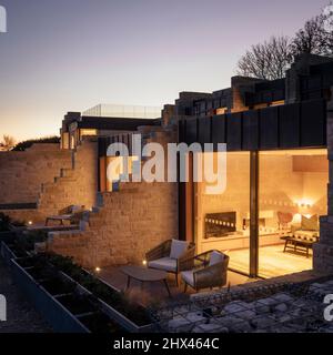 Blick von außen auf die Dämmerung von beleuchteten Fenstern und privatem Sitzbereich und Aussichtsplattform. Clifftops, Dorset, Portland, Großbritannien. Architekt: Morro Stockfoto