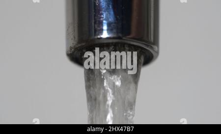 Extreme Nahaufnahme des Wassers, das aus dem Wasserhahn fließt. Verchromter Wasserhahn mit fließendem Frischwasser. Stockfoto