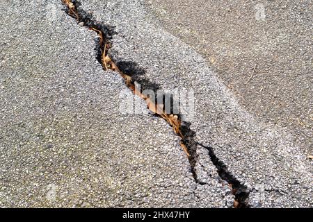 Riss in der Asphaltstraße aus nächster Nähe. Bruch der Fahrbahnoberfläche Stockfoto