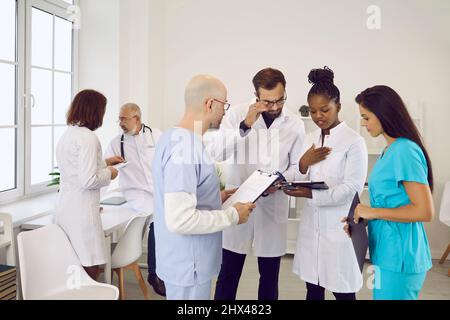Eine Gruppe von Ärzten und Krankenschwestern im Zimmer des Krankenhauspersonals diskutiert gemeinsam etwas Stockfoto