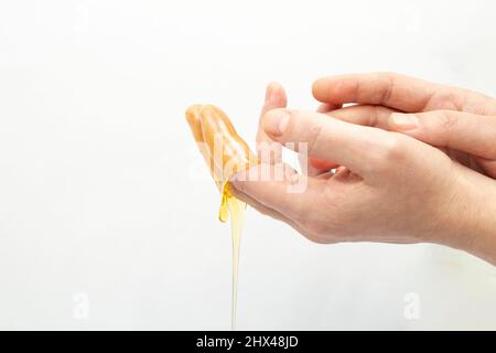 Hände der Frau, die tropfenden Honig auf die getrocknete Haut auftragen Stockfoto