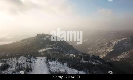 Luftaufnahme des Skigebiets mit verschneiten Pinien. Fliegen über die Ski- oder Snowboardstrecke auf weißem Schnee, umgeben von dichtem Wald in der Wintersaison, tra Stockfoto