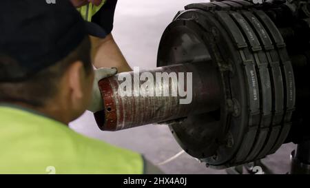 Flughafenmitarbeiter prüft Fahrgestell. Motor und Chassis des Passagierflugzeugs unter starker Wartung. Der Techniker überprüft das Chassis und den Motor des Flugzeugs Stockfoto