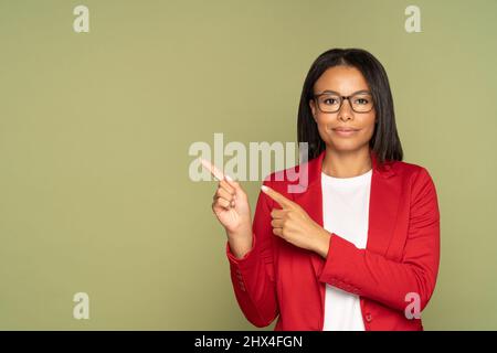 Selbstbewusste afrikanische Geschäftsfrau in roter Jacke zeigen Finger zu kopieren Raum zeigen Objekt Produkt Stockfoto