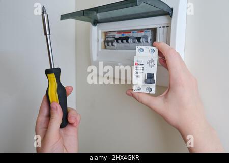 Eine Frau wechselt eine automatische Sicherung EKF in einer elektrischen Zentrale zu Hause. Selbstreparatur und Austausch von elektrischen Geräten in der Wohnung, diy - Moskau, Stockfoto