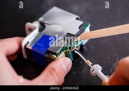 Ein Vorarbeiter repariert ein elektrisches Gerät in seinem Reparaturbüro. Stockfoto