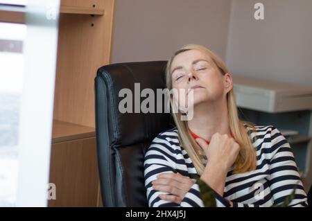 Frau, die sich im Büro ausruhte. Frau schlief in einem Bürostuhl ein Stockfoto
