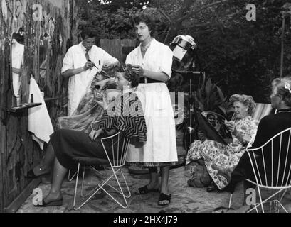 Open-Air-Friseur. Der Friseur Wuertz aus Vienne hat die vielleicht erste Open-Air-Friseureinrichtung für Damen in der Welt gegründet. Wie jede Frau weiß, kann es sehr unangenehm sein, an heißen Tagen unter dem Trockner zu sitzen. Und ihre Wusrtz-Idee von Dauerwellen im Freien hat sich weiter gefaßt. Für Australierin ist ein Sommerbesuch beim Friseur jetzt ein Vergnügen. 22. Juli 1954. (Foto von Paul Popper, Paul Popper Ltd). Stockfoto