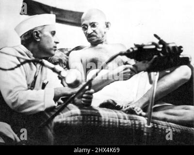 Polsterkonferenz -- Pandit Jawaharlal Nehru und Mohan das K. Gandhi, letztere bequem auf Kissen liegend, geben während der All-India Congress-Sitzung in Bombay einige Stunden vor ihrer Verhaftung am 8. August die Konferenz. Gandhi wurde heute 73 Jahre alt. Und 2.000 seiner Anhänger feisten seinen Geburtstag, indem sie Steine auf die Polizei warfen. 02. Oktober 1942. (Foto von AP Wirephoto). Stockfoto