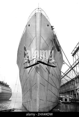 Ein Grooming in Grau -- Das Schicksal als Truppenschiff schien sich dem britischen 81.000 Luxusliner Queen Mary (oben), der am 19. März eine graue Farbe erhielt, zu stellen, während ein Bagger an ihrer Seite arbeitete und Schlamm beseitete, der seit der Auflegung der Königin bei Kriegsbeginn im vergangenen September gesammelt wurde. Rund 770 neue Männer kamen am 18. März in New York an, um die Besatzungen sowohl der Queen Mary als auch der Mauretanien zu ergänzen, und der Bericht verbreitete sich bald, dass diese Liner kanadische oder australische Soldaten transportieren könnten. 19. März 1940. (Foto von Associated Press Photo). Stockfoto