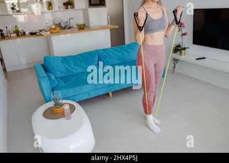 Sportliche Frau, die zu Hause mit einem Fitness-Seil trainiert Stockfoto