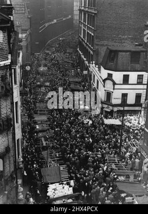 Wegen der hohen Preise für Weihnachtsartikel strömen immer mehr Londoner auf den berühmten Markt am Sonntagmorgen in der 'Petticoat Lane'. Dieses Foto, das vor einer Woche aufgenommen wurde, zeigt The Lane (der offizielle Name ist Middlesex Street), gepfercht von Ende zu Ende mit Sabbath-Schnäppchenjägern. Hier wird ein riesiger Handel mit Strümpfen, billigem Schmuck und Neuheiten durchgeführt. 09. Dezember 1950. Stockfoto