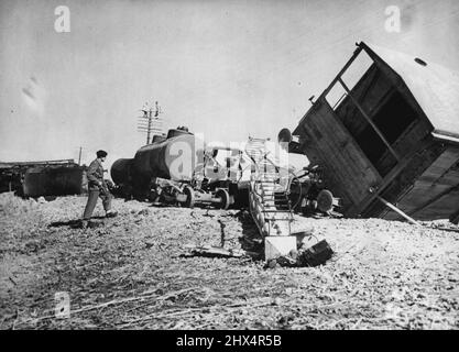 Ölzug In Der Kanalzone. Ein britischer Soldat wacht über das Wrack des Ölzuges des Kriegsministeriums, der von Terroristen in El Kap, sechs Meilen nördlich von Kantara, nördlich von Ismailia, an der Hauptlinie Port Said-Suez gesprengt wurde. Obwohl die ersten sechs Tanker des Zuges vollständig von zwei mächtigen Minen zerstört wurden, waren die einzigen britischen Opfer einige Soldaten, die an Kratzern litten. Es war der erste geplante Terroranschlag auf die Kanalzone seit den Unruhen in Kairo vor drei Wochen. 18. Februar 1952. (Foto von Associated Press Photo). Stockfoto