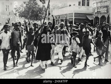 New Delhi Riots – einige der Demonstranten, darunter eine Reihe von Frauen und kleinen Kindern, werden in einer Hauptstraße in Neu Delhi mit den Armen winken, Slogans rufen und Banner tragen sehen.die Altstadt von Delhi wurde während der jüngsten Unruhen komplett abgesperrt. Demonstranten zerstörten eine Reihe von Lastwagen, drehten sie um und zündeten sie dann an. Die Schwierigkeiten begannen, als 10.000 Truppen vor lord Wavell in Neu-Delhi eine Siegesparade abhielten. Als die Unruhen ausbrachen, wurde eine Ausgangssperre verhängt und Treffen zwischen mehr als fünf Personen verboten. 27. März 1946. (Foto von Asso Stockfoto