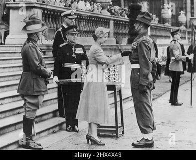 Ein Offizier erhält seine Medaille - die Königin mit Prinz Philip nahm den Gruß an einem marschposten von 2.600 Männern und Frauen aus dem Empire-Dienst, die an der Krönungsparade teilnahmen. Die Königin überreichte ihnen Medaillen. Sie ist hier zu sehen, wie sie an einer Medaille für einen neuseeländischen Offizier festpinnt. Die Zeremonie fand auf dem Rasen des Buckingham Palace statt. 03. Juni 1953. (Foto von London Express News und Feature Service). Stockfoto