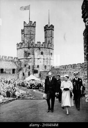 Königin und Herzog besuchen Caernarvon Castle -- Königin Elizabeth II. Und der Herzog von Edinburgh (rechts), begleitet von Lord Harlech, dem Konstabellen des Caernarvon Castle (links), folgen Sir David Maxwell Fyfe, der Innenminister, während sie durch das Gelände des Schlosses gehen, Juli 10.. Der königliche Standard fliegt vom Turm der Burg. 40.000 Menschen begrüteten die Königin, als sie heute am 10.. Juli das alte Schloss Caernarvon besuchte - die erste Königin, die die walisische Festung betreten hat, seit König Edward I. sie vor sieben Jahrhunderten gebaut hat. Auf einem Balkon über dem Tor von Königin Eleanor kam die Königin Stockfoto