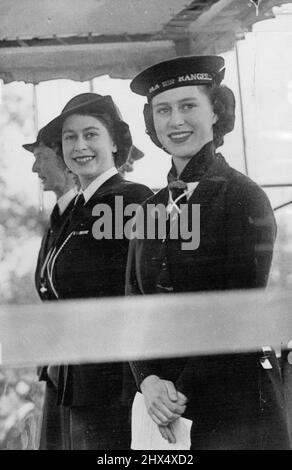 Prinzessinnen feiern bei der Girl Guides Rally. Prinzessin Elizabeth und Prinzessin Margaret nahmen an der Girl Guides Rally Teil, die heute Nachmittag im Cockpit im Hyde Park stattfand. Prinzessin Elizabeth nahm den Gruß auf dem vormarsch. Ein glückliches Foto, das Prinzessin Elizabeth und Prinzessin Margaret an diesem Nachmittag auf dem Royal Dais im Hyde Park zeigt. 10.Mai 1946. (Foto von Sport & General Press Agency Limited). Stockfoto