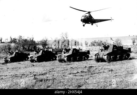 Armee-Kadetten Sehen Demonstration Durch Die Schule Der Artillerie. Die selbstfahrende Antillerie bewegt sich nach oben, während ein Hubschrauber über dem Kopf hubt, um eine bessere Unterstützung für Beobachtungszwecke zu erhalten. Kadetten der Royal Military Academy, Sandhurst, wurden Zeuge einer Demonstration der Artillerieschule in Larkhill, Salisbury Plain. Broadcast-Kommentare erläuterten die Rolle und den Einsatz der verschiedenen Ausrüstung und verschiedenen Arten von Artillerie, die die von jeder verfügbaren Feuerunterstützung zeigten, wo sie demonstriert wurden. 16. März 1948. (Foto: Sport & General Press Agency, Limited). Stockfoto