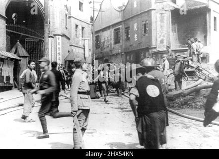 Ein A mein Beamter und Zuschauer tauchen aus Verstecken auf, um die Verwüstung dessen zu betrachten, was angeblich eine Militärstruktur in Chungking war, die während des schweren japanischen Marineangriffs auf die chinesische Hauptstadt am 4. Mai geebnet wurde. Dieses Foto, aufgenommen von einem Ausländer, wurde mit dem Boot nach Hongkong, nach Shanghai geflogen und dann hierher geflogen. 15.Mai 1939. (Foto vom Domei News Photos Service). Stockfoto