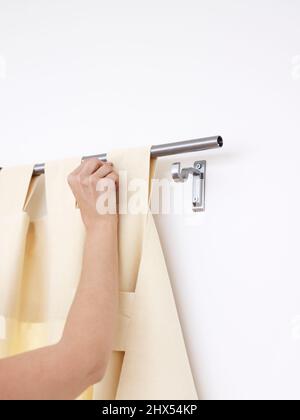Vorhänge machen, den Vorhang durch alle Schleifen führen und wieder in den Halterungen sichern Stockfoto
