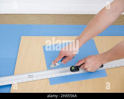 Legen eines Vinyl-Fliesenbodens, Fliesen der Kante, mit Craft Messer und Lineal, um einen Abschnitt auf dem Hartfaserplatte ausschneiden Stockfoto
