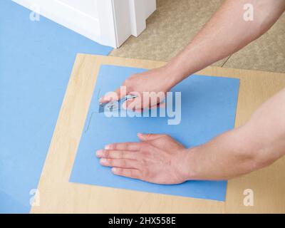 Legen Vinyl Fliese Boden, Schneiden Fliesen für Ecke, Schneiden entlang Bleistift Linie mit Handwerk Messer Stockfoto