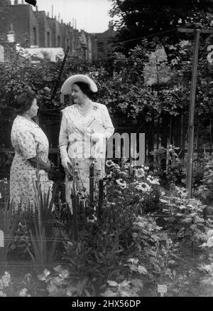 Ein königlicher Besucher im Hintergarten -- H.M. die Königin im Gespräch mit Frau Cook im Hintergarten von Bethnal Green. Während des Besuches von Gärten in der City und im Osten Londons - nach einem von der London Gardens Society organisierten Plan, richtete die Königin einen Überraschungsanruf an Herrn und Frau Cook vom Warner Place, Bethnal Green, Ost-London. Herr Cook wurde von der Gesellschaft mit mehreren Preisen für seinen Garten im Garten ausgezeichnet. 27. Juli 1949. (Foto von Sport & General Press Agency Limited) Stockfoto