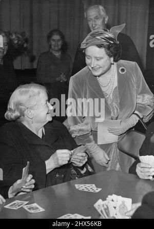 Queen Mother besucht den Old Age Pensioners Club -- die lächelnde Queen Mother sah, wie sie sich mit Mrs. Elizabeth ('Call Me Liz' Segoe (68) unterhielt, die während des Besuchs ihrer Majestät heute Nachmittag im Stepney Old Age Pensioners Club Karten spielte. H. W. Königin Elizabeth, die Königin Mutter, besuchte heute Nachmittag die Räumlichkeiten der Stepney Old People's Welfare Association in der Royal Foundation of Saint Katherine in der Metzgerei, Ratcliffe (East London). Die Queen Mother besuchte den Club der Stepney Old Age Rentner. 16. November 1955. Stockfoto