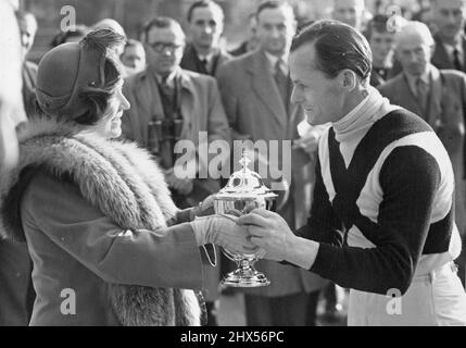 Königin Mutter im Sandown Park -- S.M. Königin Elisabeth die Königin Mutter präsentiert den Grand Military Gold Cup an LT. Col. C.H. Blacker, der die Trophäe auf seinem eigenen Pferd Pointsman gewonnen hat. Ihre Königin Elizabeth, die Königin Mutter, Ihre Königliche Prinzessin Margaret und andere Mitglieder der königlichen Familie waren heute im Sandown Park, um dort beim ersten Tag des Brand Military Meetings Rennen zu sehen. 12. März 1954. (Foto von Fox Photos). Stockfoto