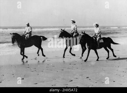 Princess Ride on African Beach - die Prinzessinnen genossen eine Auszeit von der Royal Tour durch Südafrika, als sie auf dem goldenen Sand von Bonza Beach, East London, reiten. Prinzessin Elizabeth (Mitte) reitet auf Miss Yvonne Hayhoes „Jull“, während Prinzessin Margaret auf „Treasure“ im Besitz von Pat O'Reilly reitet. Herr O'Reilly aus East London wird gesehen, wie er die Prinzessinnen eskortiert. 12. März 1947. (Foto von Reuter Photos). Stockfoto