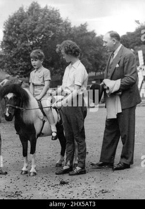 Der 5½-jährige Prinz Charles besuchte überraschend die Haustierecke im Londoner Zoo. Höhepunkt des Besuchs war eine Fahrt auf dem Pony unter der Leitung von Janet, der jungen Dame, die vielen Tausenden von Kindern als eine der Begleiter von Pets Corner bekannt ist. Auf der rechten Seite, mit Prinz-Charles-Mantel, ist der Geentdeckte, der die Partei begleitet hat. Prinz Charles hat das Interesse seiner Mutter an Pferden, aber im Moment bei Pony ist groß genug. 15. November 1954. (Foto von Stan Evans, Camera Press). Stockfoto