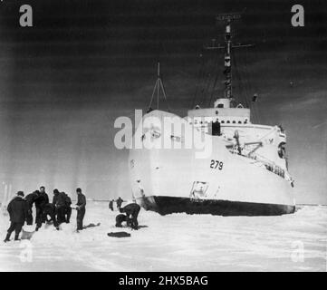 Natural Dock for Icebreaker -- der Eisbrecher Eastwind der Küstenwache ruht in einem natürlichen Eisdock in Baffin Bay, während Crew-Mitglieder versuchen, dem Drang zu genügen, aus Eisblöcken ein Eskimo-Iglu zu bauen. Der Ostwind wartete im Eis, während Hundeteams Mitglieder einer hydrographischen Mission auf die eisgebundene Baffin Island in den kanadischen Nordwest-Territorien im vergangenen Sommer trugen. Der Ostwind wurde durch Eis blockiert, das zu schwer war, als dass er 25 Meilen von der Küste von Baffin Island durchbrechen konnte. 29. Dezember 1952. (Foto von der US-Küstenwache). Stockfoto