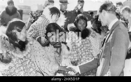 Duke Visiting Eskimos -- Ein junger Eskimo bekommt einen Tribünensitz auf den Schultern seiner Mutter, die sich verbeugt, um dem Herzog von Edinburgh, dem ersten Mitglied des britischen Königshauses, das die Arktis besucht, die Hand zu schütteln. Der Herzog traf die Eskimos in Coppermine, N.W. T. 90 Meilen im Polarkreis am Rande des kanadischen Festlandes. 10. August 19854. (Foto von AP Wirephoto). Stockfoto