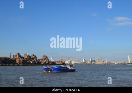 Blick von Greenwich auf die blauen Boote und die Themse hinunter zum 02 Dome im Winter an einem sonnigen Märztag. Die Skyline von London im Hintergrund Stockfoto