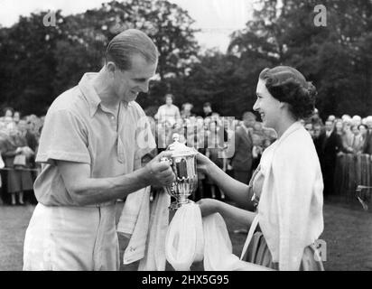 Von Der Prinzessin Zum Herzog -- Prinzessin Margaret, in türkisblauem Kleid und weißer Strickjacke, lächelt, als sie den Duke of Sutherland Cup dem Duke of Edinburgh überreichte, nachdem das Cowdray-Park-Team die Windhunde im Finale beim Polo-Turnier im Cowdray Park Midhurst Sussex heute besiegt hatte. (Pfingstmontag). Die Prinzessin hatte mit dem Herzog aus Windsor vertrieben. 07. Juni 1954. (Foto von Reuterphoto). Stockfoto