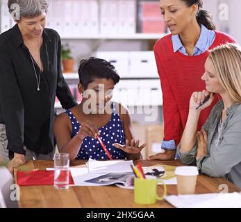 Diskussion führt zur Perfektion. Eine kurze Aufnahme einer Gruppe von Frauen, die in einem Sitzungssaal über Bilder diskutieren. Stockfoto